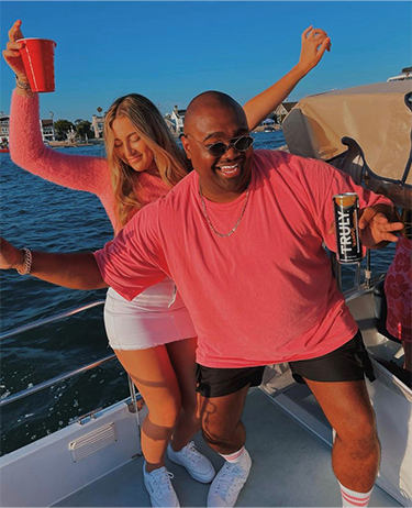 Woman and man on a boat dancing and holding cans of Truly Hard Seltzer