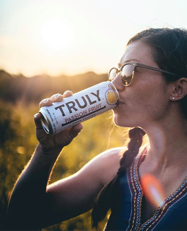Woman drinking from a can of Truly Hard Seltzer